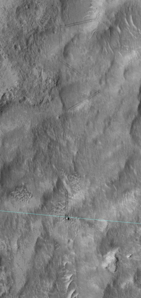 El 27 de junio, la cámara HiRISE de la sonda Mars Reconnaissance Orbiter (Orbitador de Reconocimiento Marciano, o MRO por sus siglas en inglés) fotografió a Curiosity en la superficie del planeta rojo, poco después de que el rover finalizara un recorrido de 82 metros que lo dejó justo en el borde de su elipse de aterrizaje. La misma está representada por la línea de color celeste sobreimpresa en la imagen. Créditos: NASA/JPL-Caltech/University of Arizona.